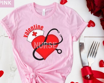 May include: Pink t-shirt with a Valentine's Day theme. The shirt features a red heart with the word "NURSE" and a nurse's hat and stethoscope graphic. The word "Valentine" is above the heart.
