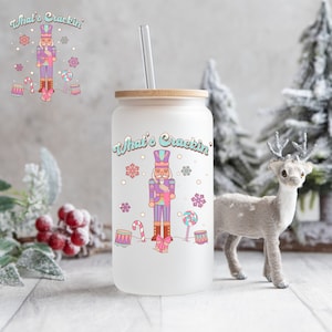 May include: A frosted glass tumbler with a bamboo lid and a straw. The tumbler features a colorful illustration of a nutcracker, candy canes, and drums. The text "What's Crackin'" is printed on the tumbler.