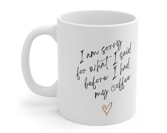 May include: White ceramic coffee mug with black text that reads "I am sorry for what I said before I had my coffee" with a gold heart at the bottom.