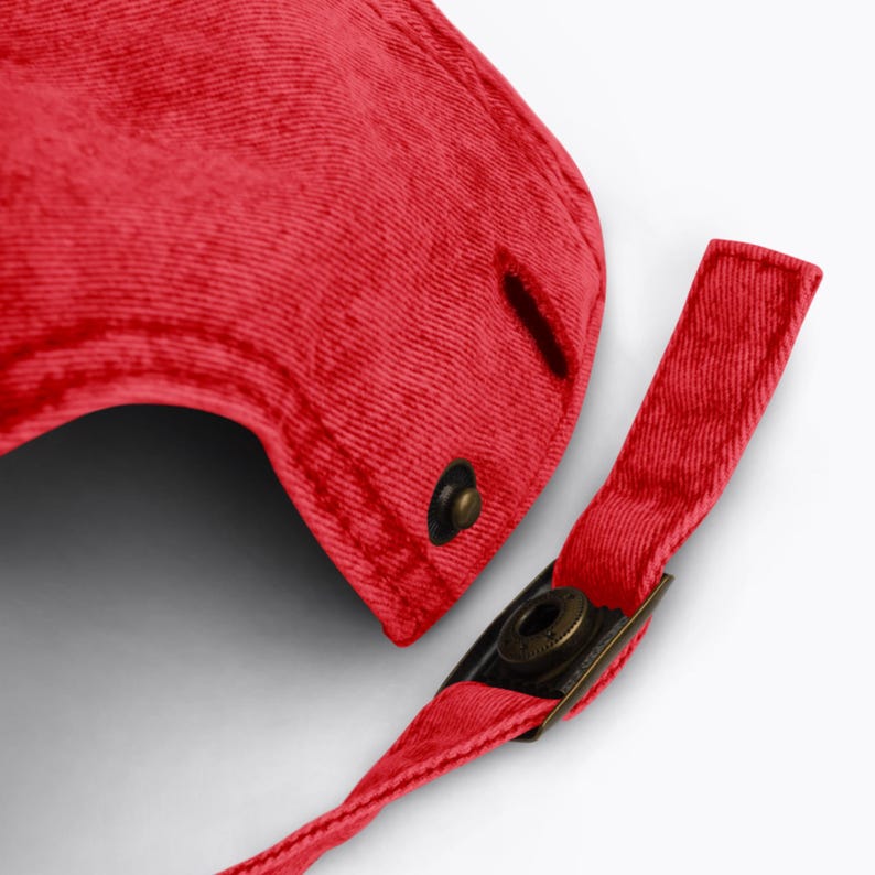 May include: Red baseball cap with a fabric strap and a metal buckle. The strap is adjustable.