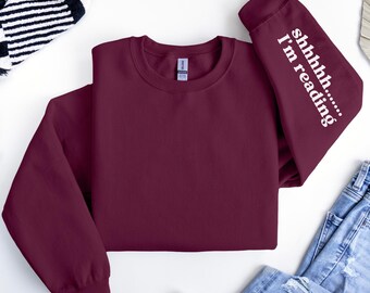 May include: Burgundy sweatshirt with the text "shhhh... I'm reading" on the sleeve.