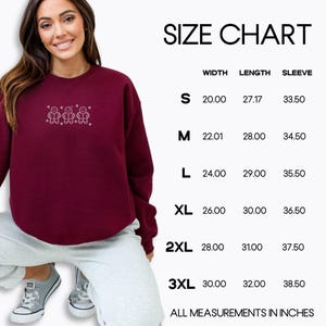 Pode incluir: Camisola bord&ocirc; com bonecos de gengibre e flocos de neve bordados. A tabela de tamanhos mostra as medidas em polegadas para largura, comprimento e manga para os tamanhos S a 3XL. O texto diz "SIZE CHART".