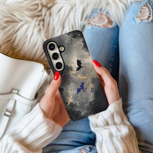 Könnte beinhalten: Schwarze Smartphone-Hülle mit einem dramatischen Wolkenhimmel-Design und drei fliegenden Drachensilhouetten in Schwarz, Gold und Blau. Die Hülle hat einen schwarzen Rand und ein Kameramodul.