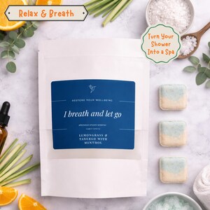 May include: A white pouch with a blue label that reads "I breath and let go" and "Lemongrass & Tangelo with Menthol." The image also shows three shower steamers and the text "Turn Your Shower Into a Spa."