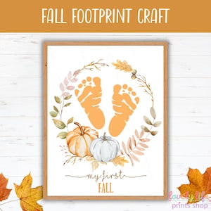 May include: A framed print with the text "FALL FOOTPRINT CRAFT." The artwork features orange footprints, pumpkins, and fall foliage. The words "my first FALL" are written below the pumpkins.