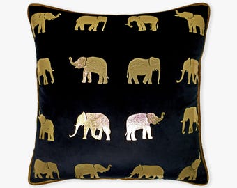 May include: A black velvet pillow with a gold elephant pattern. The pillow has a brown trim.