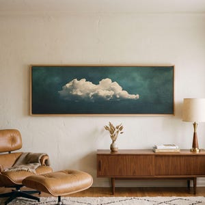 May include: A panoramic rectangular wall art piece featuring a single white cloud centred against a deep teal and dark green textured background, enclosed in a light-toned wooden frame, displayed horizontally above a wooden sideboard.