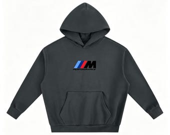 Può includere: Una felpa con cappuccio grigio antracite scuro dotata di una tasca a marsupio frontale e maniche lunghe. Al centro del petto è presente il logo M Performance, che include tre strisce inclinate di colore azzurro, blu scuro e rosso, seguite dalla M.