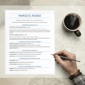 May include: A CV titled "MARCO S. RUSSO" with contact details, experience, qualifications, and skills. A coffee cup is beside the CV, and a hand holding a pencil is positioned over the document.