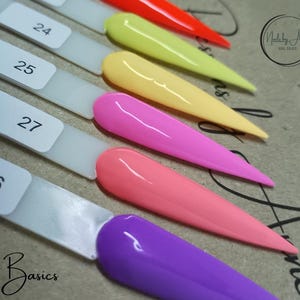 Könnte beinhalten: Ein Set mit sechs Nagellackfarben in einem Regenbogen-Verlauf. Die Farben sind Lila, Rosa, Orange, Gelb, Grün und Blau. Die Farben werden auf einem weißen Hintergrund mit den Nummern 24, 25, 26 und 27 angezeigt.