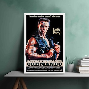 May include: A movie poster for the action film Commando starring Arnold Schwarzenegger. The poster features a close-up of Schwarzenegger in a black tank top, holding a gun and looking intensely at the viewer. The text on the poster reads "Somewhere, somehow, someone's going to pay. Let's Party!" and "Schwarzenegger Commando".