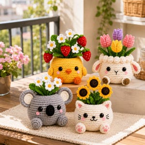 May include: Four crocheted animal-shaped planters containing various flowers and fruits. A yellow chick holds strawberries and daisies, a cream sheep holds tulips, a grey koala holds daisies, and a white cat holds sunflowers.