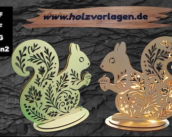 May include: Two wooden squirrel cutouts with intricate floral designs. One is light green, the other is gold. Each squirrel holds an acorn. The website "www.holzvorlagen.de" is displayed above the squirrels. The image also shows the file types: DXF, PDF, SVG, and Lbrn2.