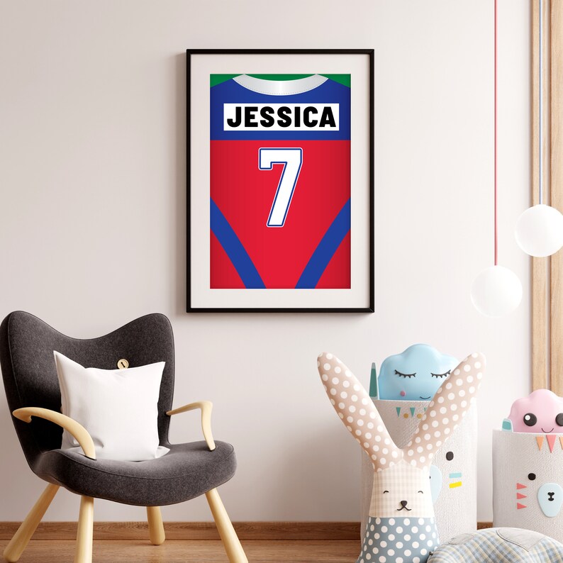 Puede incluir: Una impresi&oacute;n enmarcada de una camiseta roja, azul y verde con el nombre "Jessica" y el n&uacute;mero "7" en ella.