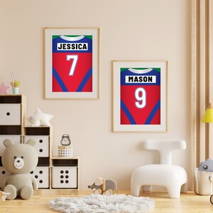 Puede incluir: Dos impresiones enmarcadas de camisetas deportivas rojas, azules y verdes con los nombres "Jessica 7" y "Mason 9" impresos en ellas.