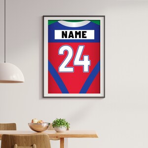 Puede incluir: Una impresi&oacute;n enmarcada de una camiseta deportiva roja, azul y verde con el n&uacute;mero 24 y la palabra "NAME" en ella.