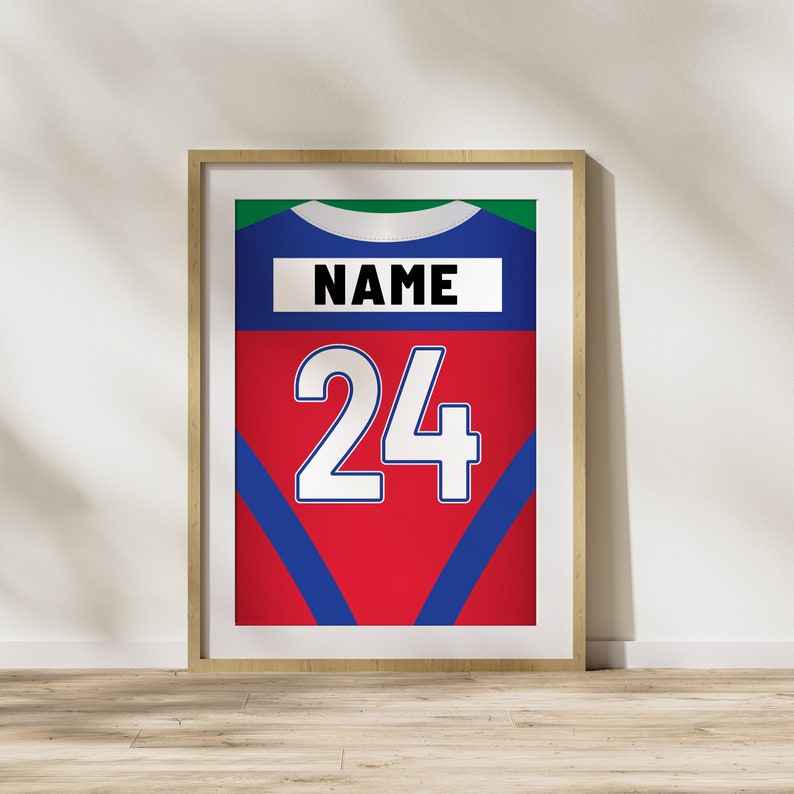 Puede incluir: Una impresi&oacute;n enmarcada de una camiseta roja, azul y verde con el n&uacute;mero 24 y la palabra "NAME" en ella.