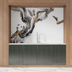 Puede incluir: Un dise&ntilde;o de cocina moderno con un mueble gris oscuro de cuatro puertas, una encimera blanca y un grifo de acero inoxidable. El salpicadero muestra una llamativa obra de arte abstracta en tonos negro, blanco y dorado. Las paredes circundantes est&aacute;n revestidas de madera marr&oacute;n claro.