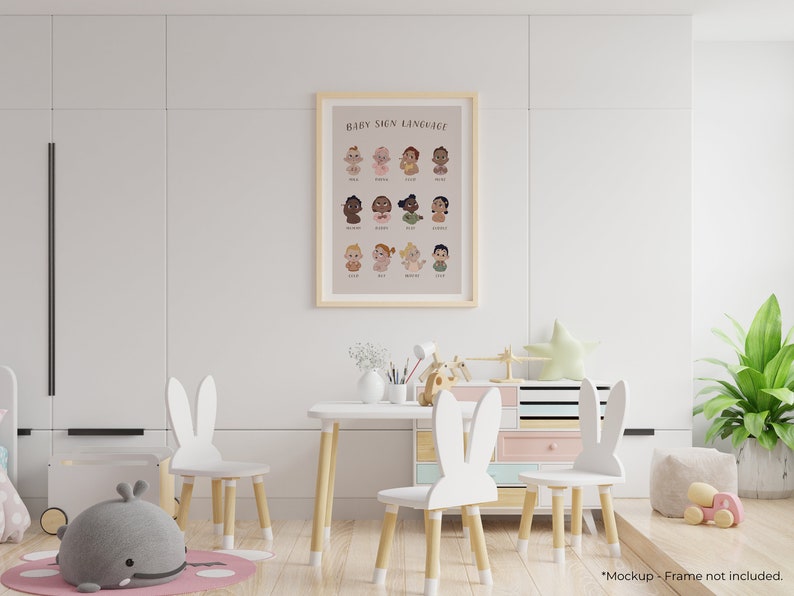 May include: A white framed poster with the text "Baby Sign Language" and illustrations of babies signing different words. The poster is hanging on a white wall in a playroom with a white table and chairs with bunny ears.