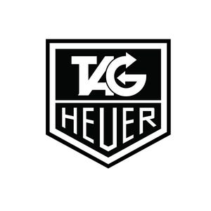 以下が含まれることがあります： 上部にTAG、下部にHEUERという文字が配置された、白黒の盾型ロゴ。デザインは太い枠線で水平に分割されており、コントラストの強いグラフィックエンブレムとして、太字のレタリングが特徴的なデザインとなっています。