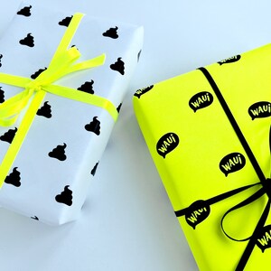 Könnte beinhalten: Zwei Geschenkboxen. Eine Box ist weiß mit einem schwarzen Kack-Emoji-Muster und einem gelben Band. Die andere Box ist leuchtend gelb mit einem schwarzen Sprechblasenmuster, auf dem "WAUI" steht, und einem schwarzen Band.