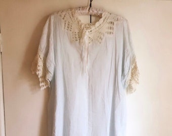 Puede incluir: Un camisón azul claro con cuello y mangas de crochet blanco.