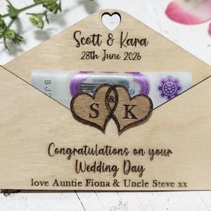 May include: A wooden wedding card holder shaped like an envelope. It features a heart-shaped cutout and the names "Scott & Kara" with the date "28th June 2026". The text "Congratulations on your Wedding Day" is also visible. The holder has a heart-shaped cutout.