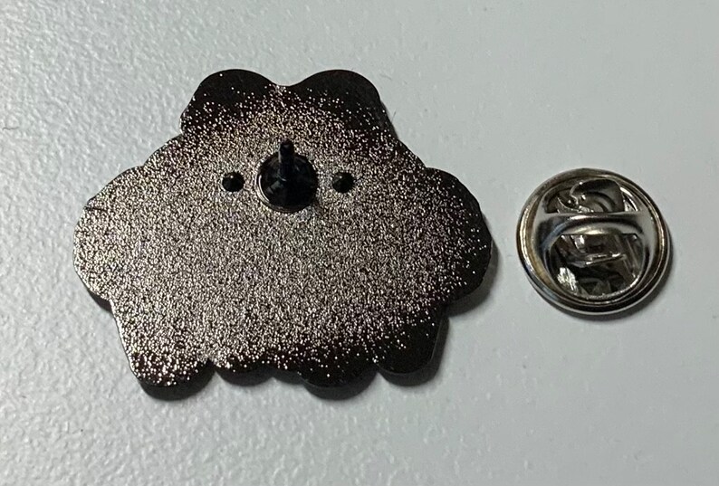 May include: The back of a silver metal pin with a black rubber backing. The pin is shaped like a cloud with a textured surface. The pin has a silver metal clasp.