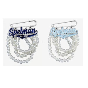 May include: Two silver-toned safety pin brooches featuring the text Spelman Est. 1881 in blue and light blue enamel. Each brooch is adorned with multiple cascading strands of white faux pearls of varying sizes, creating a layered, dangling effect.