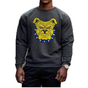 K&ouml;nnte beinhalten: Dunkelgraues Sweatshirt mit einem gelben Bulldoggen-Motiv und einem blauen Stachelhalsband. Der Bulldogge hat einen strengen Ausdruck. Das Sweatshirt ist ein Rundhals-Stil und scheint aus einem weichen Material zu sein.