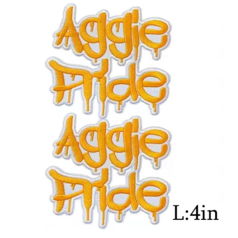 K&ouml;nnte beinhalten: Zwei gelbe, gestickte Aufn&auml;her mit den Worten "Aggie Pride" in einer tropfenden Schriftart. Die Aufn&auml;her sind wei&szlig; umrandet. Die L&auml;nge der Aufn&auml;her betr&auml;gt 10,16 cm.