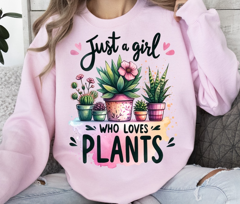 Może przedstawiać: R&oacute;żowa bluza z napisem "Just a girl who loves plants" i akwarelowym wzorem doniczkowych roślin.