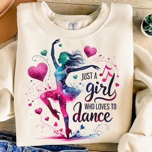 May include: A cream-colored sweatshirt with a colorful graphic of a dancer and the text "Just a girl who loves to dance".