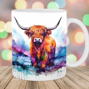 May include: White ceramic mug featuring a colourful watercolour illustration of a Highland cow with long horns. The background is a watercolour wash of purple, blue and green.
