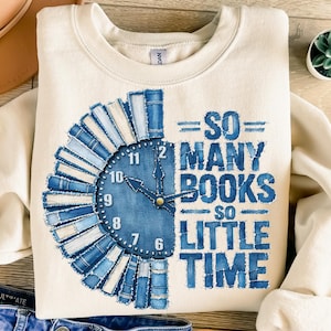 Może przedstawiać: Kremowa bluza z nadrukiem w kolorze niebiesko-białym. Grafika przedstawia tarczę zegara z książek z napisem "SO MANY BOOKS SO LITTLE TIME". Bluza ma okrągły dekolt i długie rękawy.