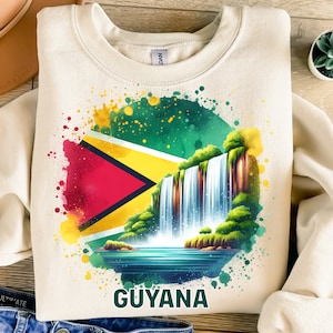 May include: A beige sweatshirt with a watercolor design featuring the flag of Guyana and a waterfall. The text "GUYANA" is printed below the design.