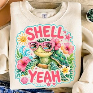 Op de afbeelding: Een crèmekleurige sweater met ronde hals en een grafische print van een groene zeeschildpad met een roze zonnebril. Het ontwerp bevat de tekst "SHELL YEAH" in roze letters, omringd door kleurrijke hibiscusbloemen, een zon en zeeschelpen.