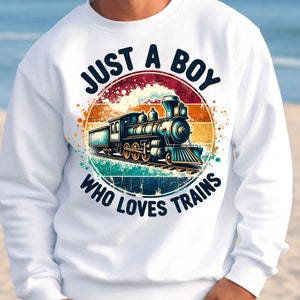 May include: White sweatshirt with a vintage-style graphic of a train and the text "Just a Boy Who Loves Trains".