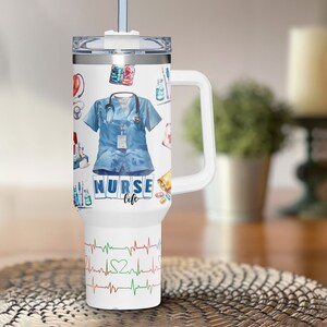 May include: White insulated tumbler with a handle, featuring a design of medical equipment, a blue scrub top, and the words "NURSE life." The bottom of the tumbler has a colorful EKG heartbeat design.