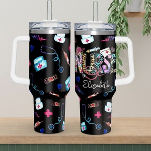 May include: Two black stainless steel travel mugs with a white handle and lid. The mugs feature a colorful pattern of medical symbols, including a stethoscope, bandages, and a syringe. The word "NURSE" is written in large, colorful letters on one mug, with the name "Elisabeth" written below.