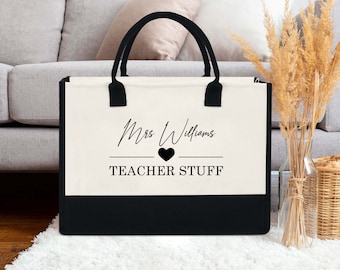 May include: A white canvas tote bag with black handles and a black bottom. The bag has the text "Mrs. Williams" in a cursive font with a heart symbol and the text "TEACHER STUFF" printed on it.