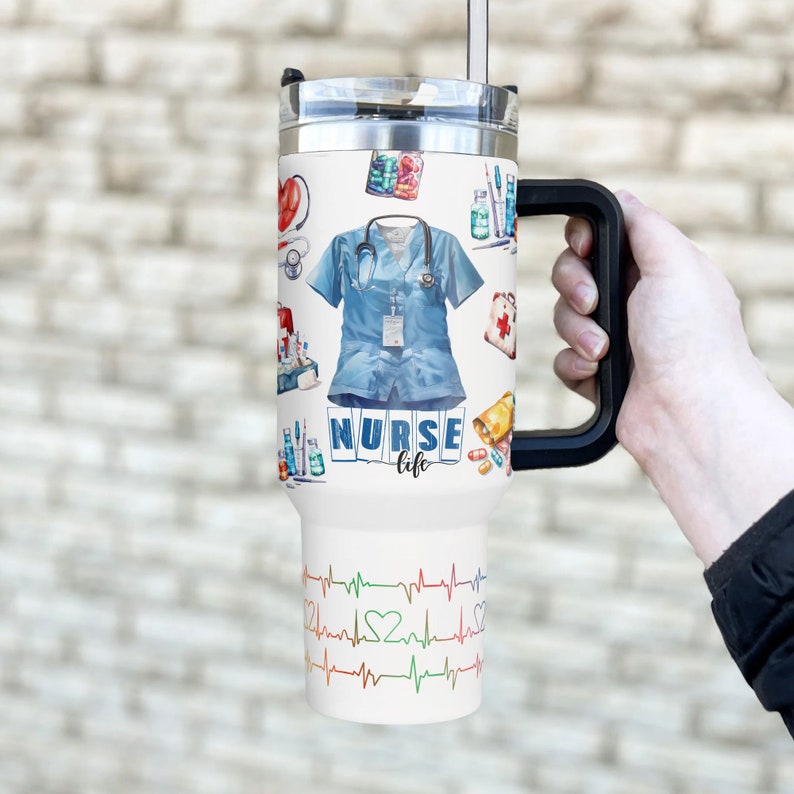 May include: White travel mug with a black handle, featuring a watercolor design of medical supplies, a nurse's uniform, and the text "NURSE life." The bottom has a colorful EKG heartbeat design.