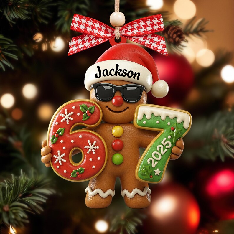 May include: A gingerbread man Christmas ornament wearing sunglasses and a Santa hat with the name "Jackson". The ornament holds the numbers "6" and "7" with the year "2025". The ornament is decorated with red, white, and green icing and is hanging from a red and white bow.