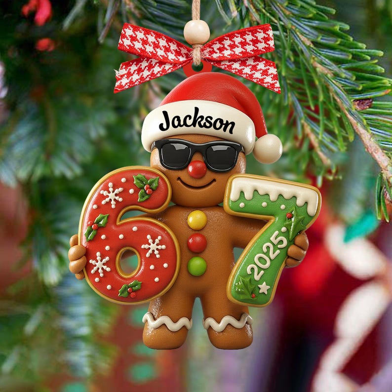 May include: A gingerbread man Christmas ornament wearing sunglasses and a Santa hat with the name "Jackson" on it. The ornament holds the numbers "6" and "7" with the year "2025" on the "7". The ornament is decorated with red, white, and green icing.