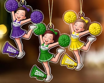 May include: Three acrylic cheerleader ornaments in purple, green, and yellow, each with a cheerleader design, pom-poms, and a megaphone with "2025". Each ornament has a name: Amelia, Chloe, and Sophia.
