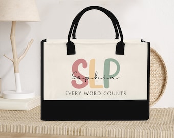 May include: A white canvas tote bag with black handles and black trim. The bag has the letters "SLP" in colorful block letters with the name "Sophia" written in cursive underneath. The text "EVERY WORD COUNTS" is printed below the name.