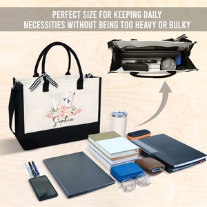 May include: A canvas tote bag with black handles and a black bottom. The bag features a floral design with the name "Sophia" and the text "PERFECT SIZE FOR KEEPING DAILY NECESSITIES WITHOUT BEING TOO HEAVY OR BULKY". The bag is open, revealing its contents.