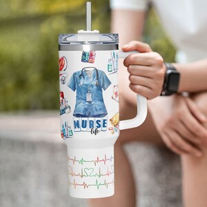 May include: White tumbler with a handle, featuring a design of medical supplies, a blue nurse's uniform, and the words "NURSE life." The bottom of the tumbler has a colorful heartbeat design.