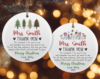 May include: Two white, round Christmas ornaments with gold string hangers. One features green Christmas trees, the other colorful flowers. Both have the text "Mrs. Smith ♥ THANK YOU ♥ Merry Christmas Love, Emily 2025."