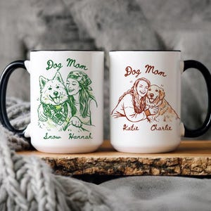 Może przedstawiać: Dwa białe ceramiczne kubki z czarnymi uchwytami i obramowaniami. Każdy kubek przedstawia rysunek kobiety z psem, napisy "Dog Mom" oraz imiona psa i właściciela. Jeden kubek ma zielone akcenty, drugi brązowe.